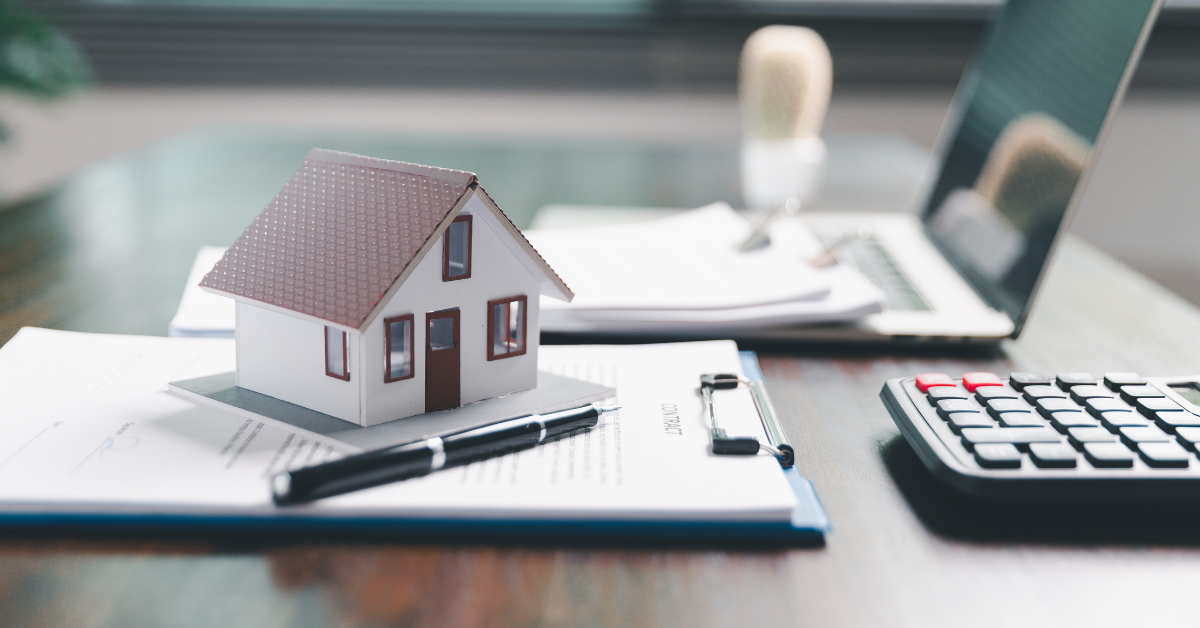 A model house on a clipboard with a laptop in the background representing property ownership types